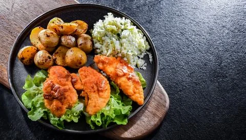Breaded chicken cutlets served with potatoes and cabbage. Stock Photos
