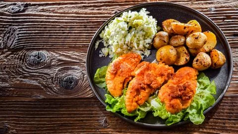 Breaded chicken cutlets served with potatoes and cabbage. Stock Photos