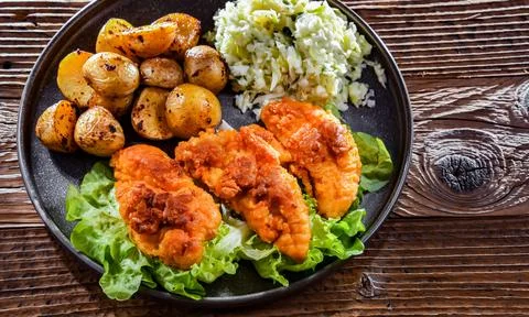 Breaded chicken cutlets served with potatoes and cabbage. Stock Photos