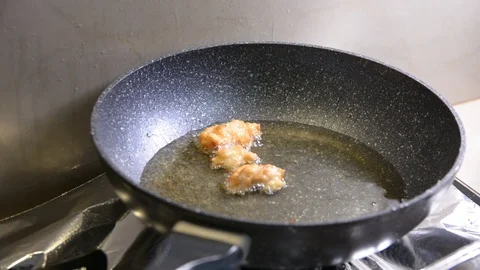 Breaded chicken deep frying in oil in a cast iron frying pan Vídeos de archivo 95653927