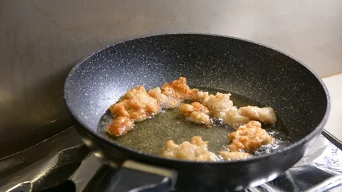 Breaded chicken deep frying in oil in a cast iron frying pan Видео 95656679
