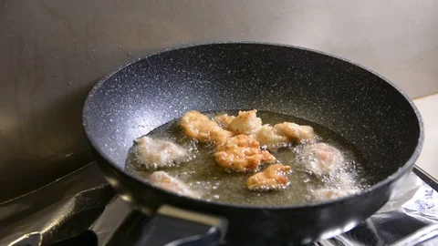 Breaded chicken deep frying in oil in a cast iron frying pan Vídeo Stock 95658065