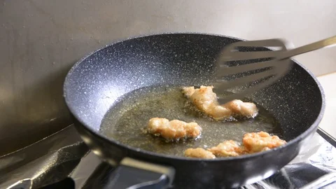 Breaded chicken deep frying in oil in a cast iron frying pan 스톡 동영상 95658293