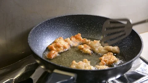 Breaded chicken deep frying in oil in a cast iron frying pan Vídeos de archivo 95658441