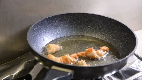 Breaded chicken deep frying in oil in a cast iron frying pan Vídeo Stock 95659589