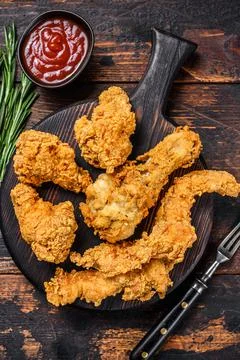 Breaded chicken drumstick, leg, wing and breast tenders strips. Dark Wooden Stock Photos