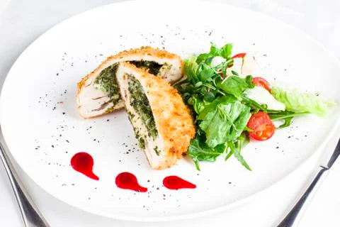 Breaded chicken fillet stuffed with spinach with fresh vegetables and herbs Stock Photos