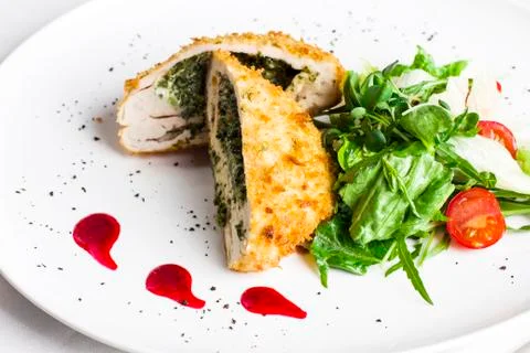 Breaded chicken fillet stuffed with spinach with fresh vegetables and herbs Stock Photos