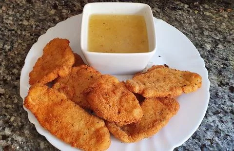 Breaded chicken, fried and with lemon sauce. Foto stock