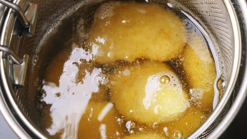 Breaded chicken nuggets in a deep-frying net are fried in boiling oil on th.. Stock Footage 303712384