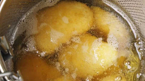Breaded chicken nuggets in a deep-frying net are fried in boiling oil on th.. 库存影片 304374862