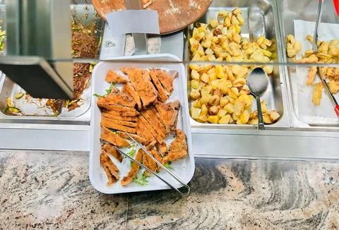 Breaded Chicken Strips and Roasted Potatoes on a Buffet Table Foto stock