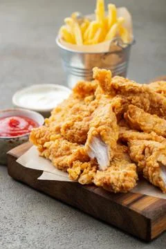Breaded chicken strips with two kinds of sauces and fried potatoes on a woode Foto stock