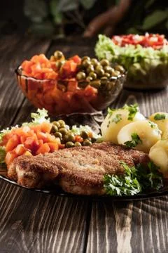 Breaded chop and potatoes. dark light. Stock Photos