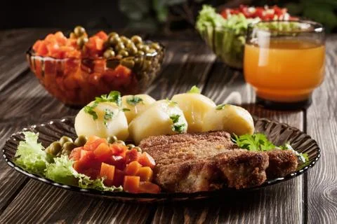 Breaded chop and potatoes. dark light. Stock Photos