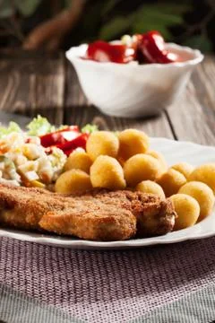 Breaded chop, prepared potatoes and salad. mysterious light. Stock Photos