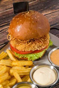 Breaded crispy chicken burger with tomato lettuce and fries Stock Photos
