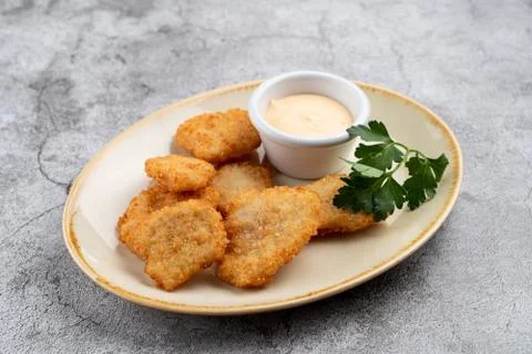 Breaded crispy chicken nuggets with cheese sauce on grey table Stock Photos