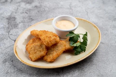 Breaded crispy chicken nuggets with cheese sauce on grey table Stock Photos