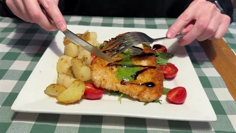 A breaded cutlet is being cut with a knife and fork Stock Footage 318078310