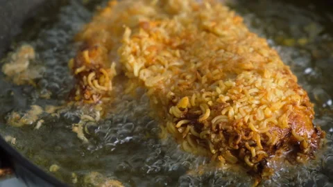 Breaded in dry noodle chicken breast frying in hot oil in pan on stove. Stock Footage 311885731
