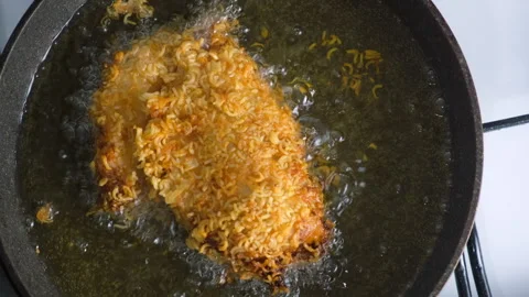 Breaded in dry noodle chicken breast frying in hot oil in pan on stove. Stock Footage 311885829