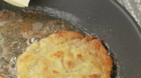 Breaded escalopes being fried in a pan with a knob of butter being added to the 스톡 동영상 24636930