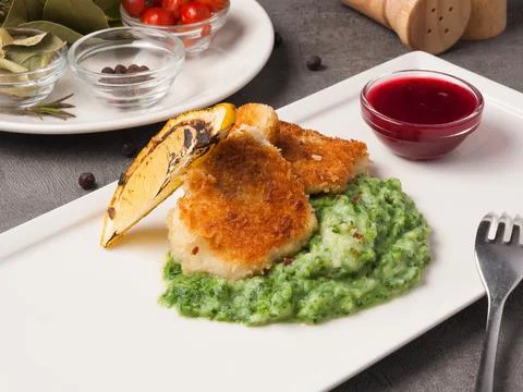 Breaded fish fillet with spinach puree garnish Stock Photos