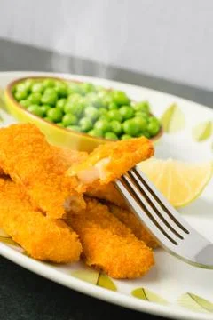 Breaded fish fingers with peas Stock Photos