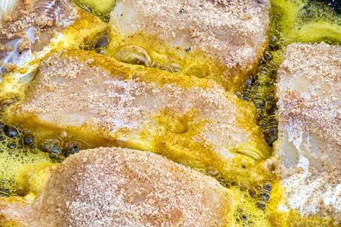 Breaded fish steaks, fried in a pan with vegetable oil. Stock Photos