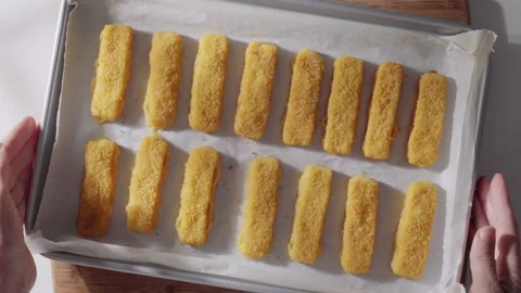 Breaded fish sticks are arranged in neat rows on parchment paper just from the o Stock Footage 321849573