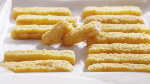Breaded fish sticks are arranged in neat rows on parchment paper just from the o Stock Footage 321864018