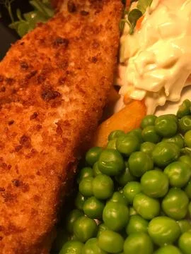 Breaded Haddock with peas, chips and coleslaw - on a white plate Stock Photos
