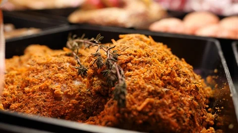 Breaded pieces of raw beef meat with rosemary are lying in black tray in the Stock Footage 106232250