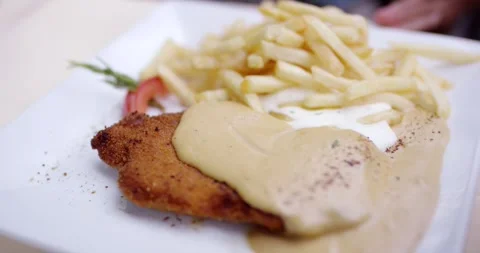 Breaded schnitzel with creamy sauce and crispy french fries on a plate Vídeo Stock 339872182