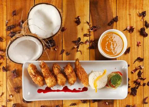 Breaded shrimp with Coconut shell in Jamaican sauce, accompanied by steamed r Stock Photos