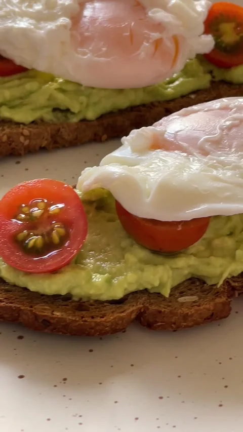 Breads with avocado cream, cherry tomatoes and poached eggs. Stock Footage 287860546