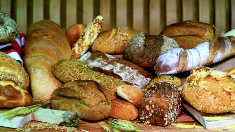 Breads from different types and styles displayed on wooden surface with wheat 動画素材 325098878