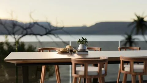 Breads on plate next to coffee cup on a long table with armchair on terrace.. Illustrazione stock