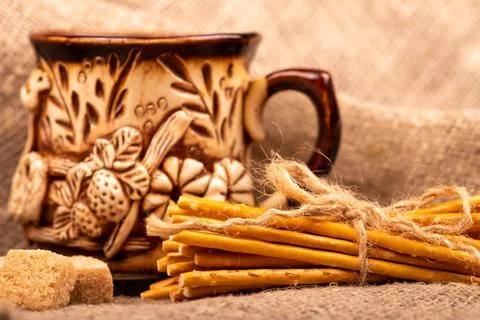 Breadsticks with salt tied with string and an earthenware mug for tea. Close- Stock Photos