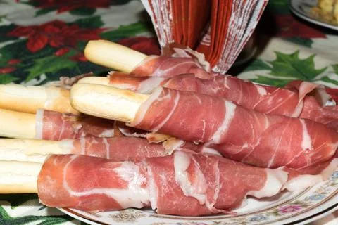 Breadsticks wrapped with thin slices of ham Stock Photos