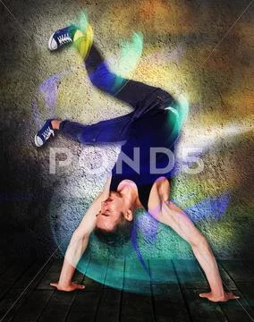 Break dancer doing handstand against colorful wall background Stock Photos
