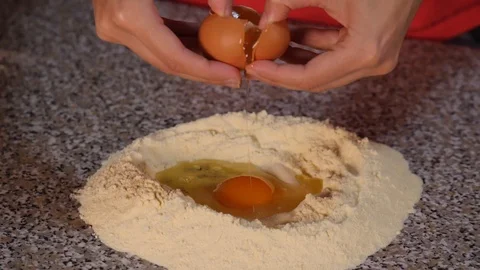 Break an egg into the flour - Slow Motion Stock Footage 98173311