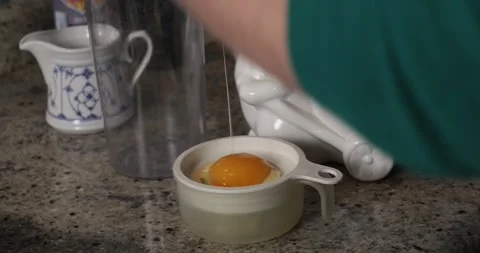 Break egg with knife, separate whites from yolks closeup. Kitchen space in Stock Footage 311937740