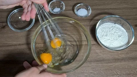 Break eggs and mix eggs with a metal whisk in a bowl Stock Footage 164155778