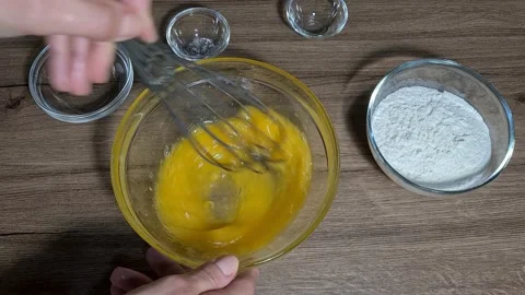 Break eggs and mix eggs with a metal whisk in a bowl Stock Footage 164155788
