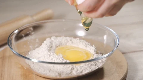 Break eggs into flour, close up and slow motion Stock Footage 120604276
