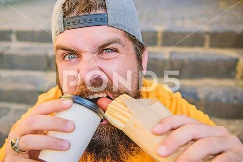 Break free of hunger and thirst. Bearded man having hot dog and coffee for snack Stock Photos
