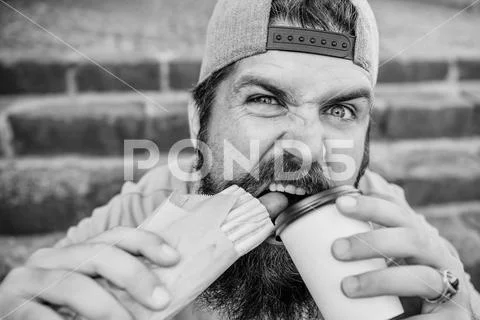 Break free of hunger and thirst. Bearded man having hot dog and coffee for snack Stock Photos