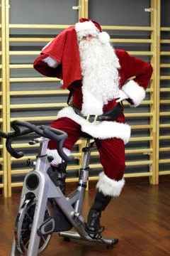 Break - Santa Claus training on exercise bike at the gym Stock Photos